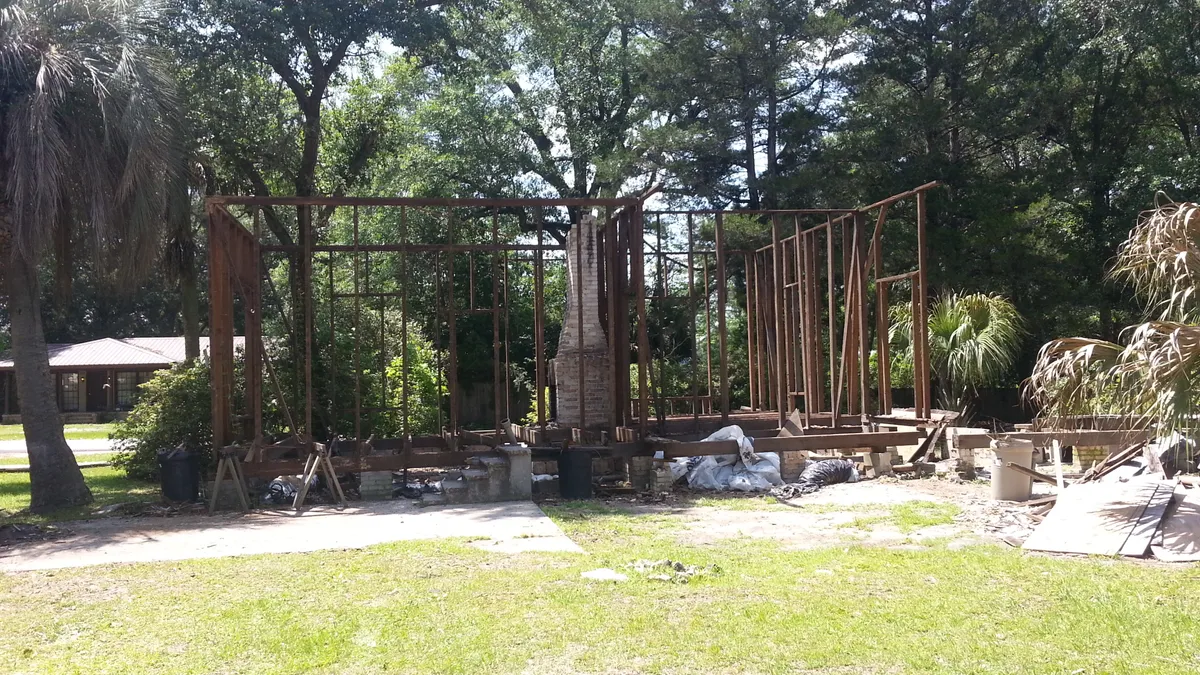Remaining wood wall framing and chimney after removal of the roof and siding.