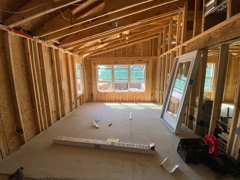 Framed addition interior with a vaulted ceiling and large windows.