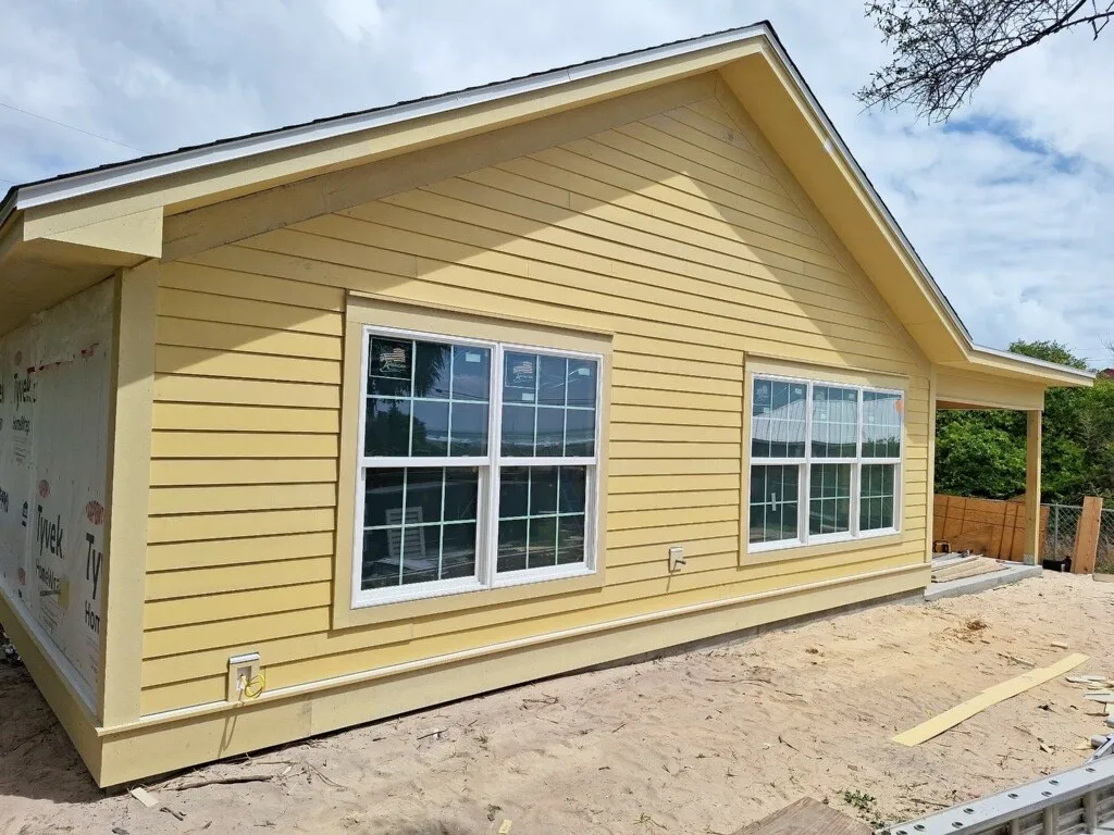 Addition exterior with unpainted lap siding and two large groups of windows.