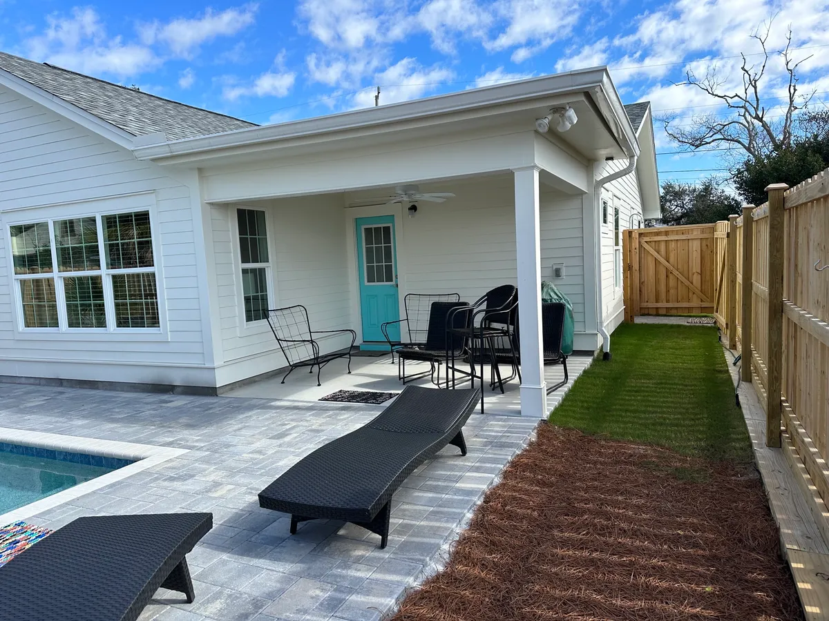 Covered rear porch with white trim, a turquoise door, ceiling fan, and outdoor seating.