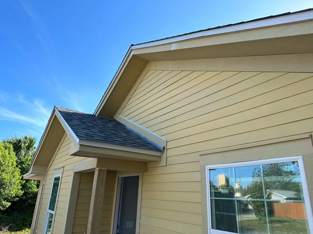 Close view of the front gables, siding, trim, and flashing where the porch roof meets the wall.