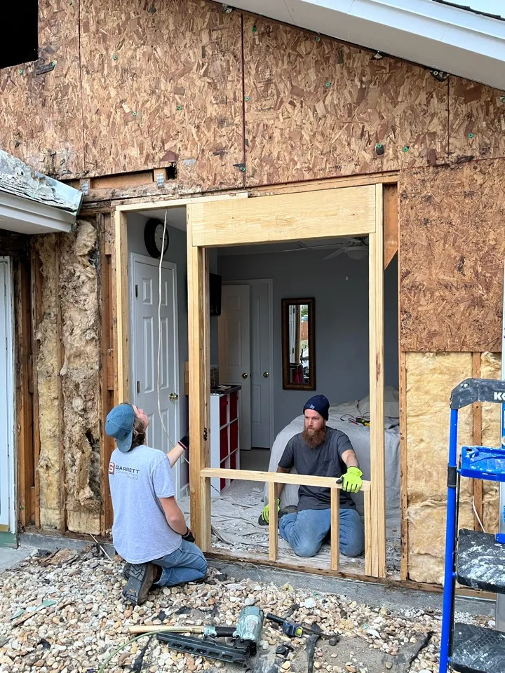 Two crew members rebuilding a window opening in the exposed exterior wall.