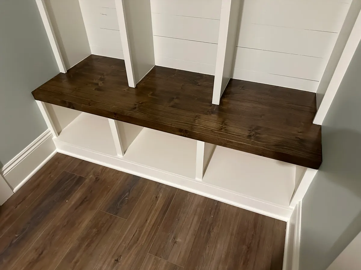 Close view of a stained wood bench with open storage compartments beneath.