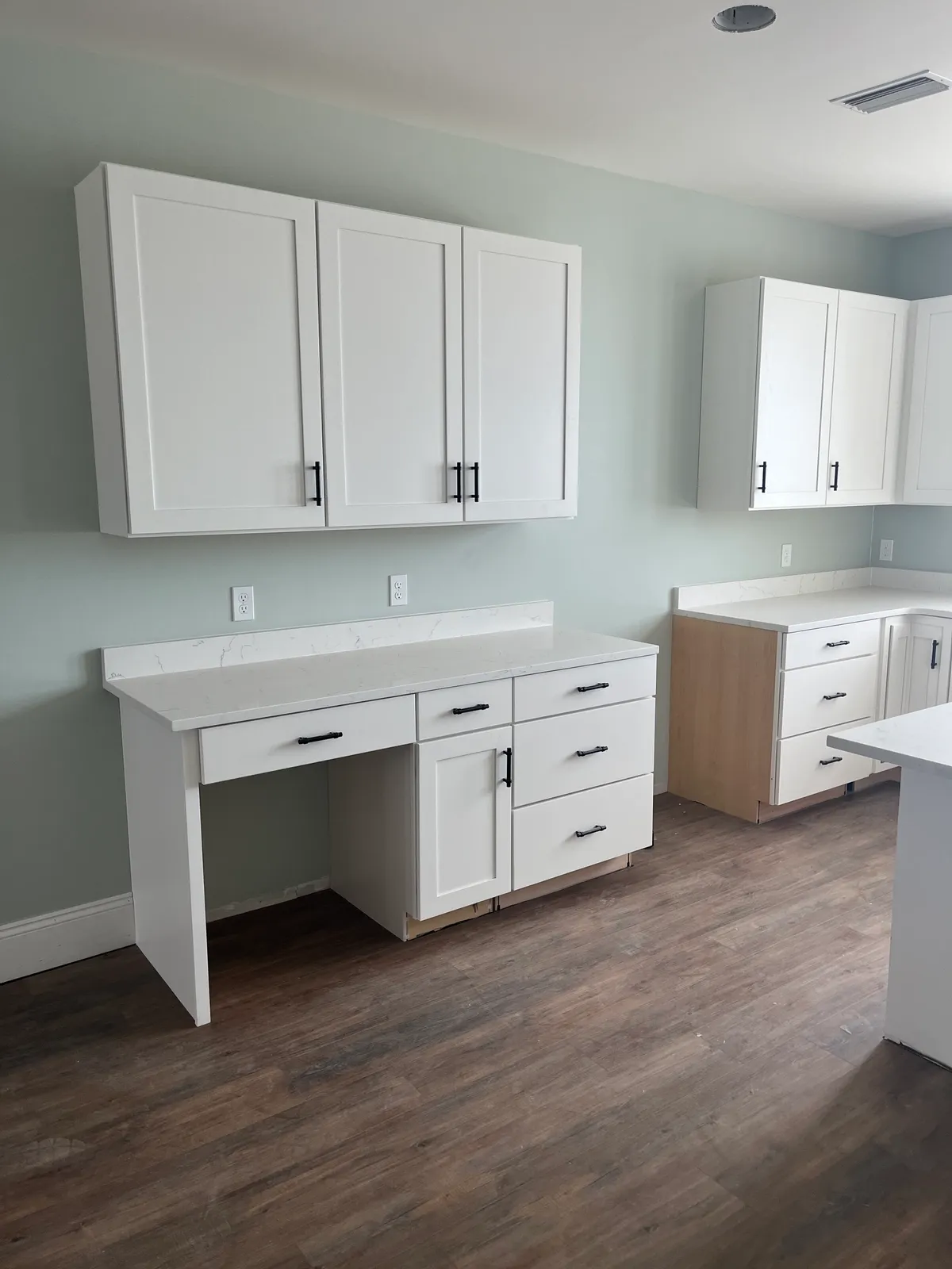 Counter-height cabinetry with knee space and upper cabinets beside the kitchen.