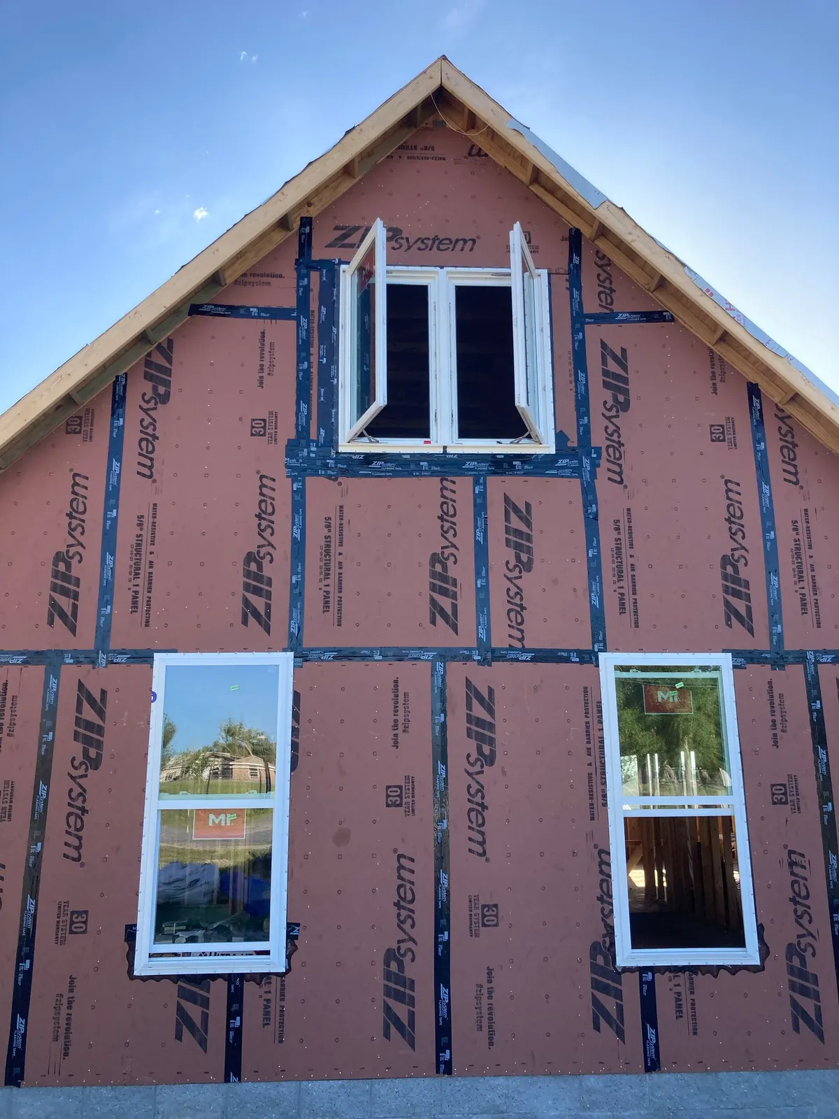 Gable end sheathed in ZIP System panels with taped seams and newly installed windows.