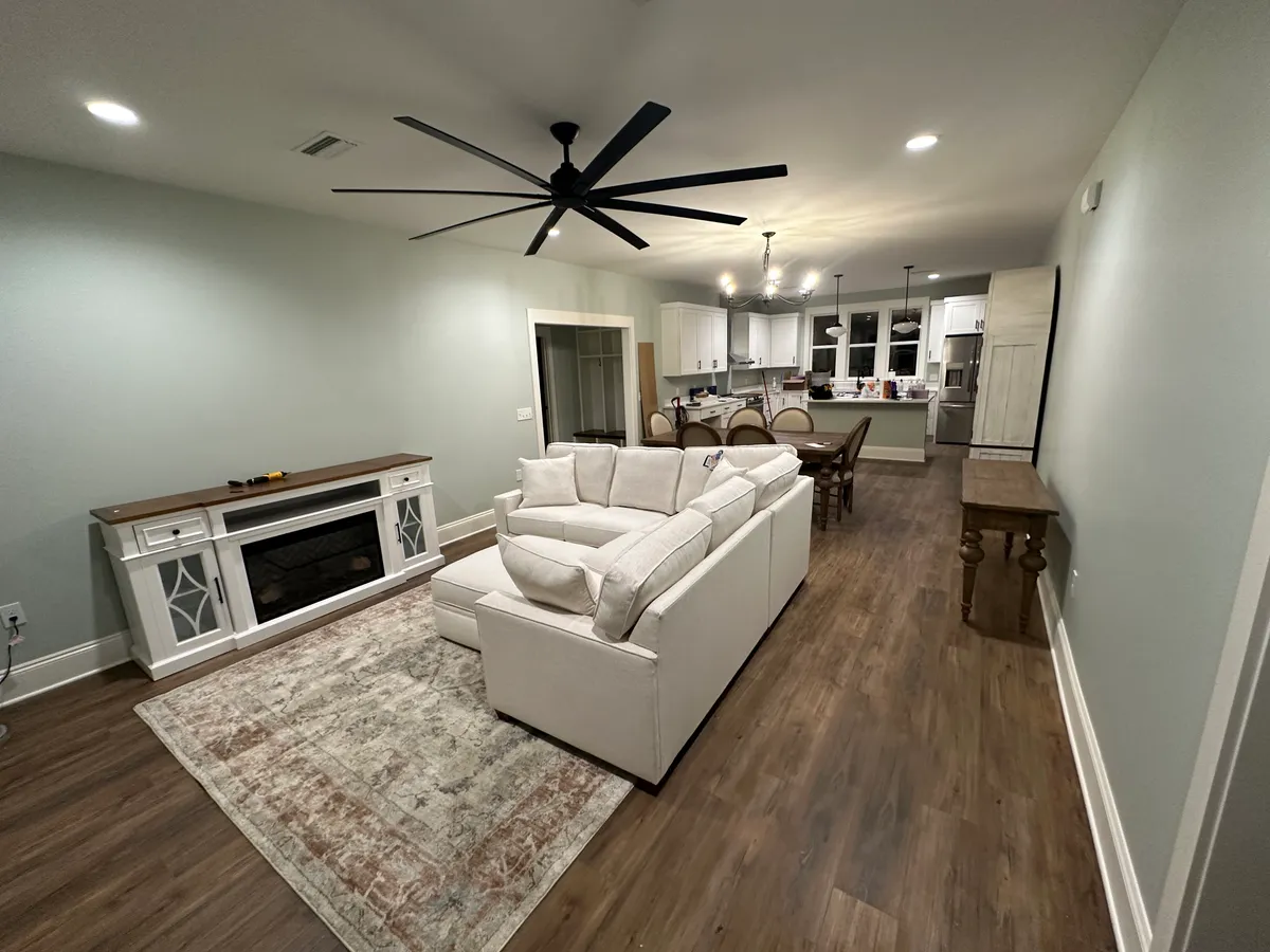 Living room with a sectional sofa and ceiling fan, open to the dining area and kitchen beyond.