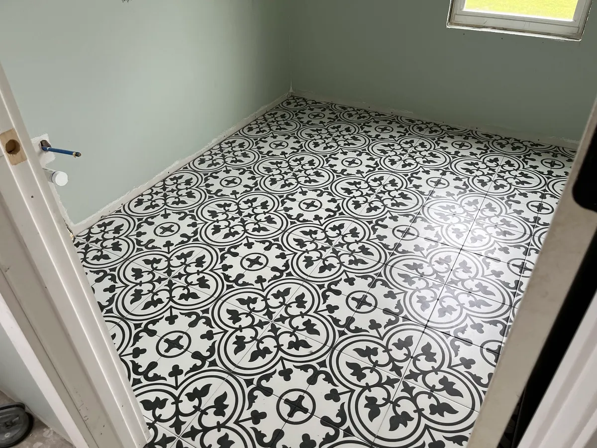 Small room with black-and-white patterned floor tile and a capped plumbing connection on the wall.