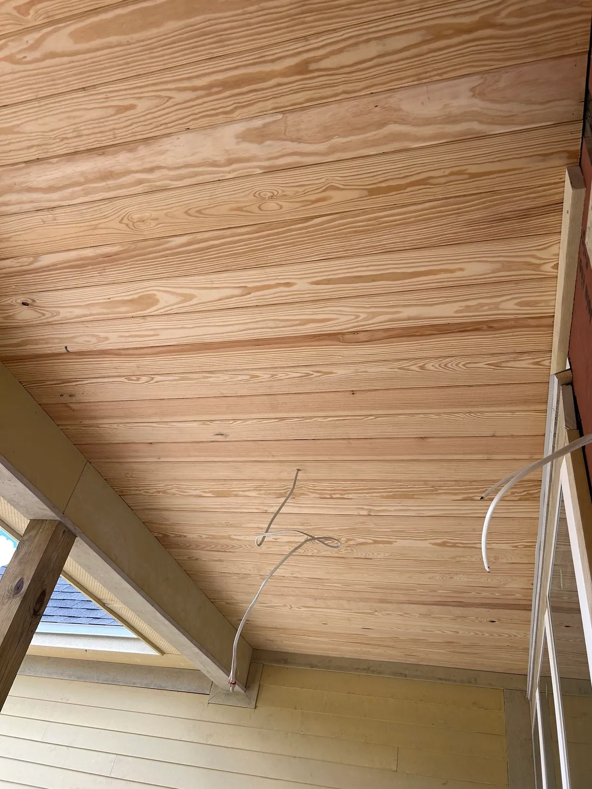 Wood plank porch ceiling with electrical wires waiting for light fixtures.