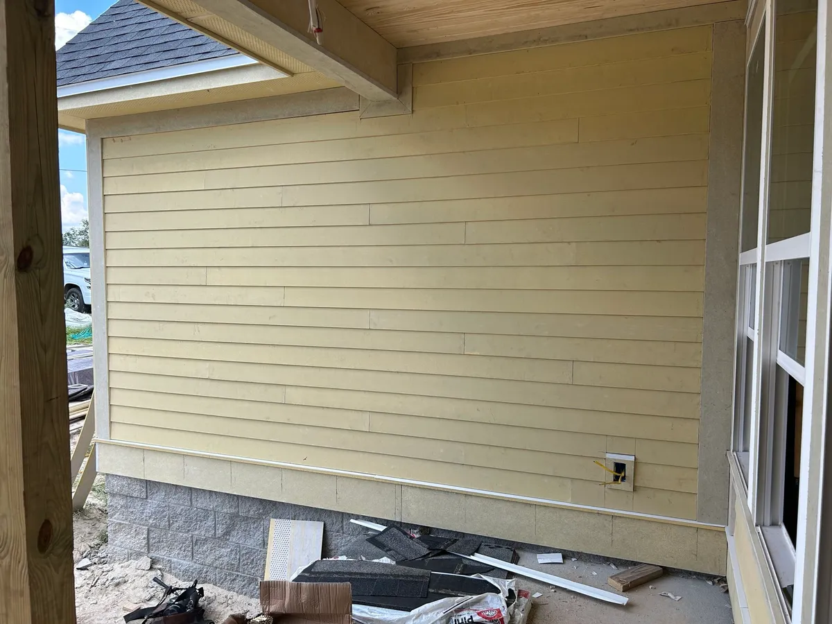 Unpainted yellow siding on a covered porch wall above the stemwall, with construction debris below.