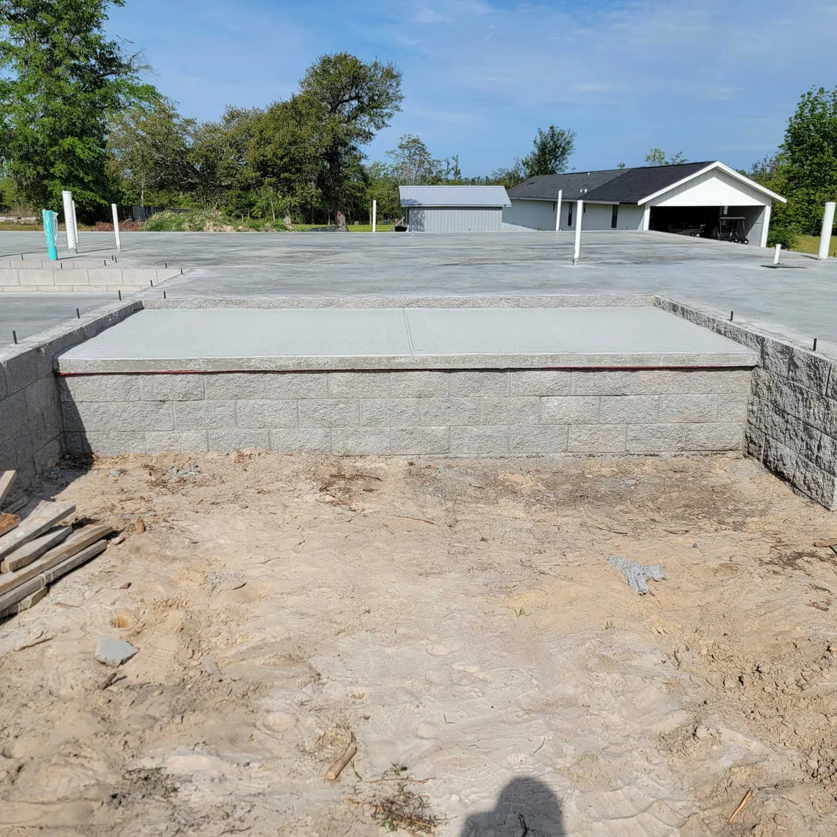 Poured concrete slab edged by the split-face block stemwall, with sand fill in the foreground.
