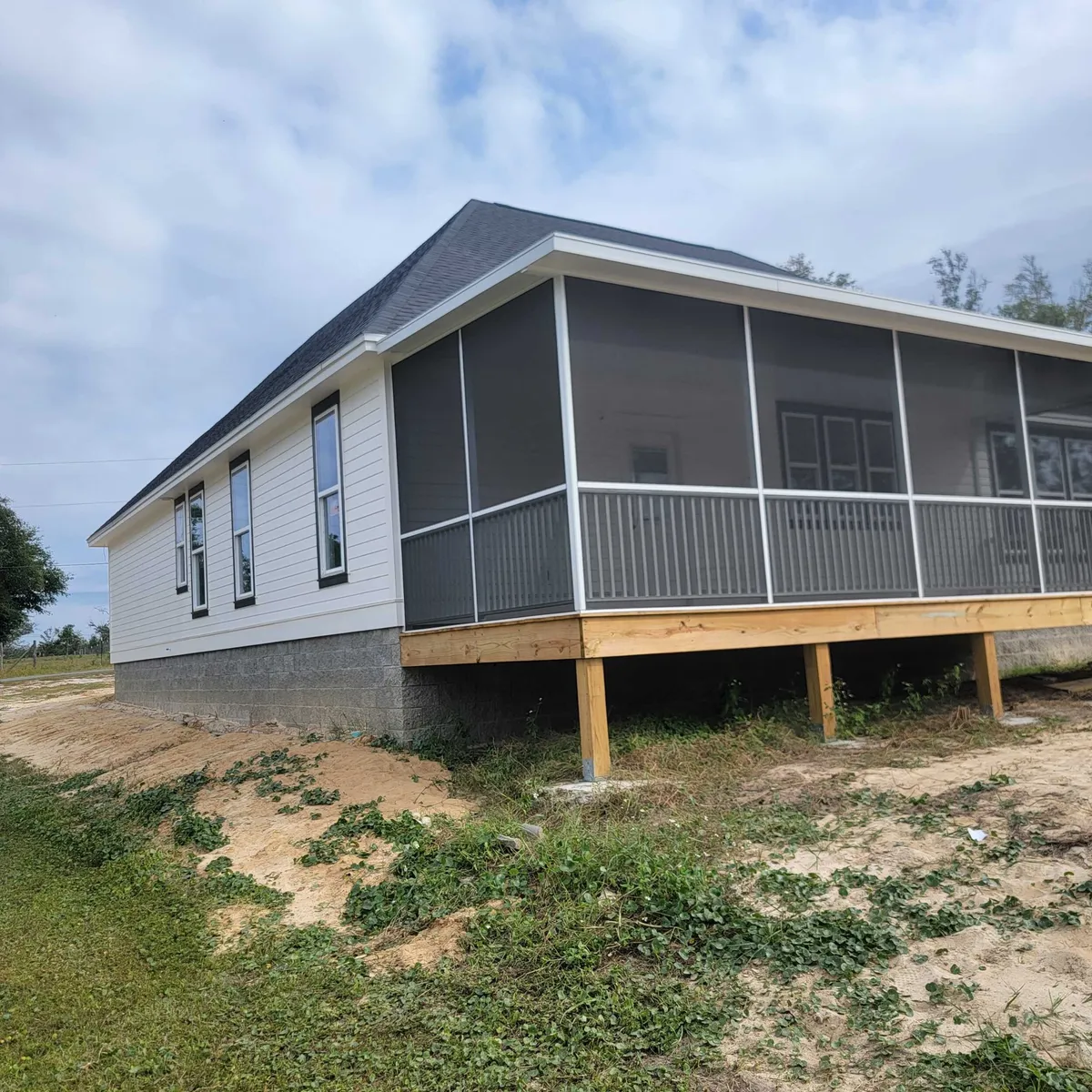 Side of the house with a screened porch on wood posts and the split-face stemwall visible along the base.
