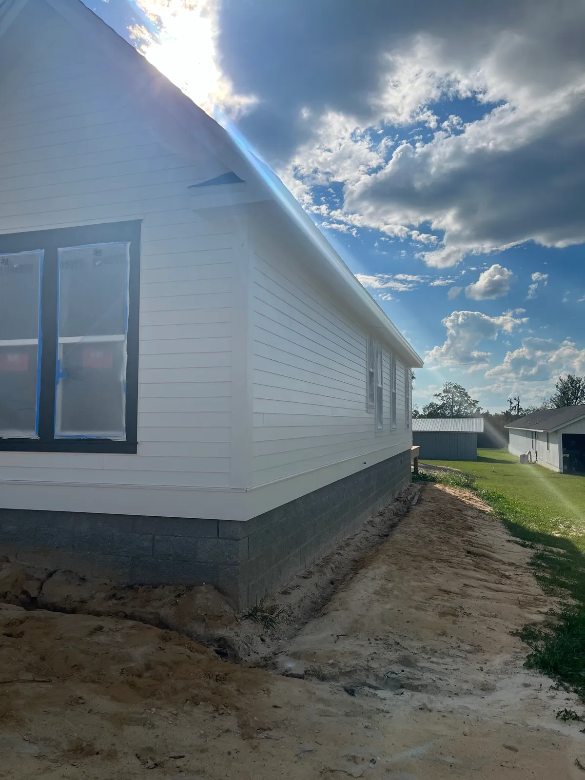 Painted siding and windows along the side of the house above the exposed split-face stemwall.