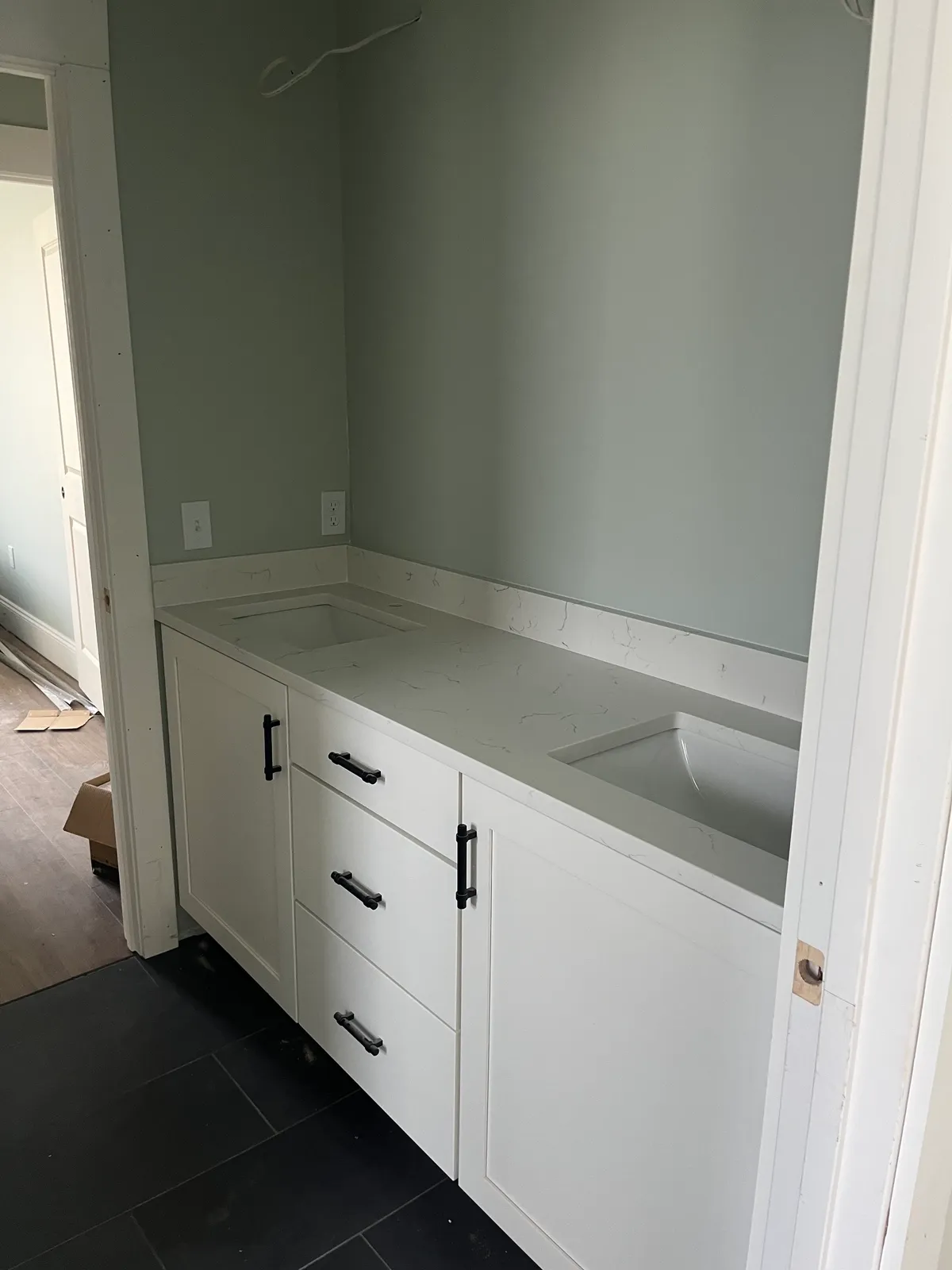 Double-sink vanity with white cabinets and a light counter, before faucets were installed.