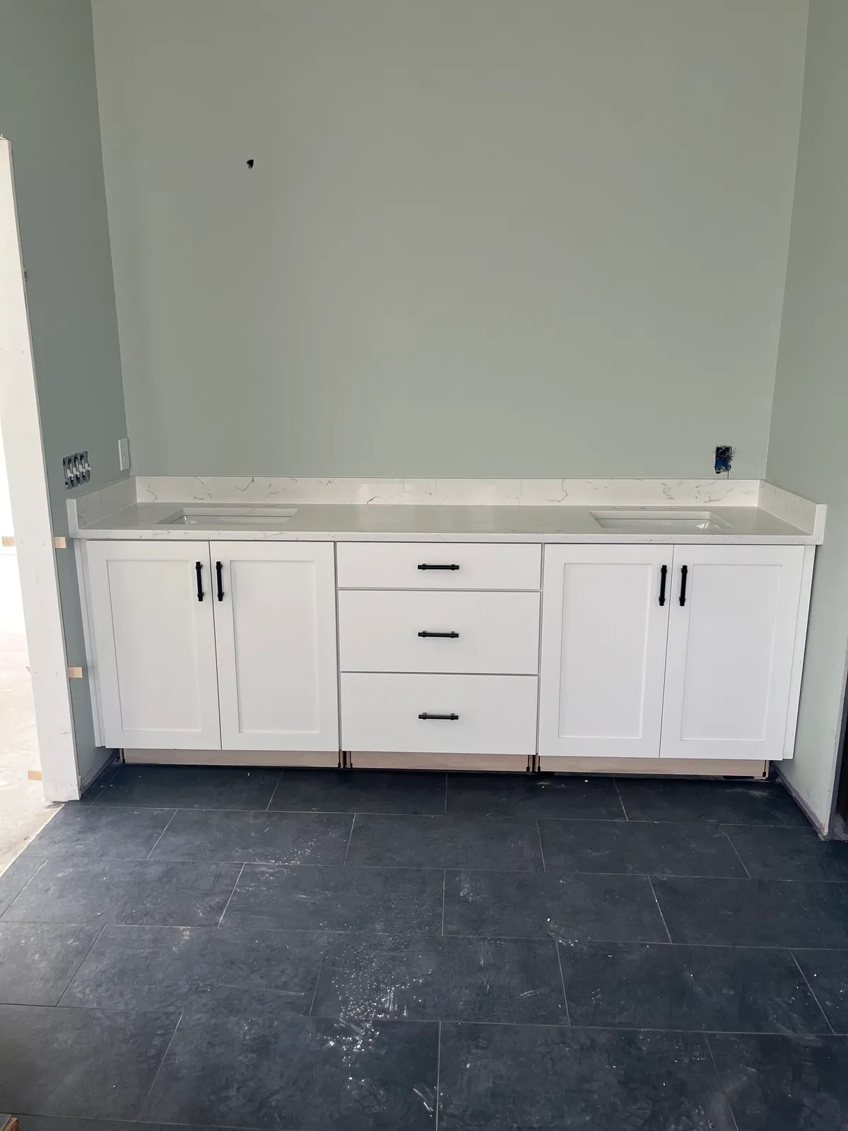 Double vanity with drawers and cabinet doors on dark floor tile, before faucets were installed.