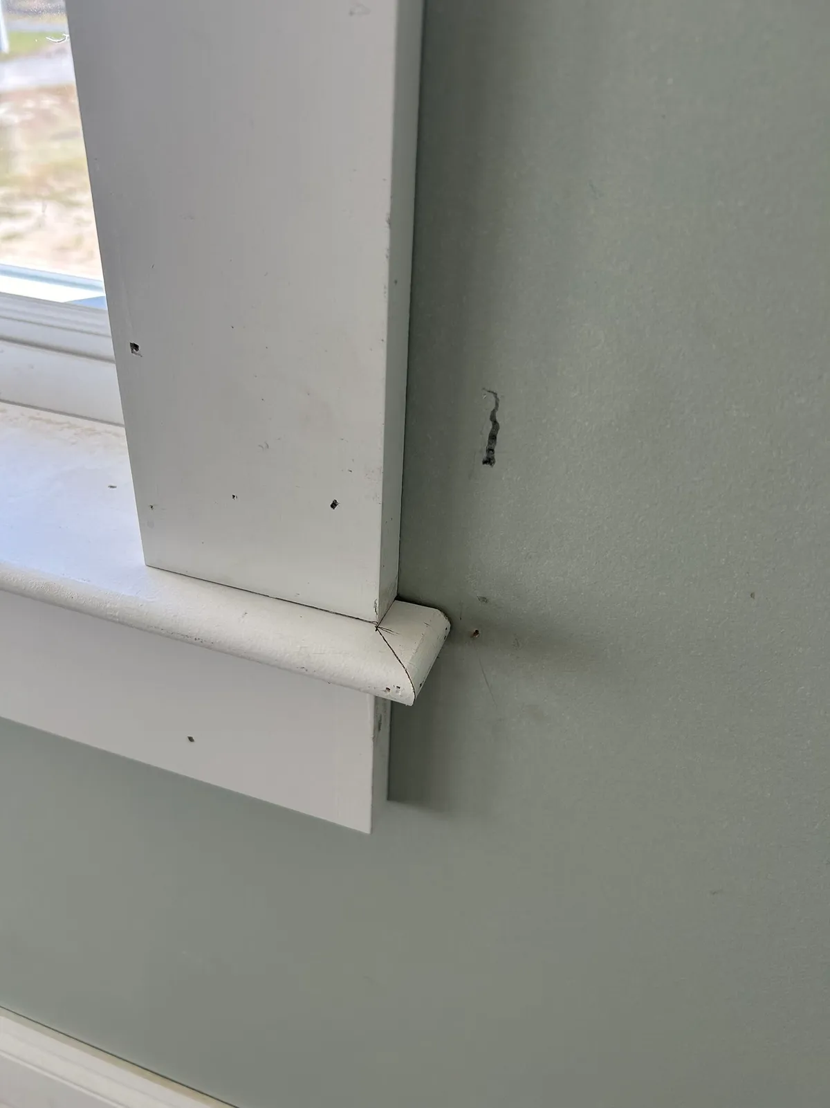 Close view of a window stool and casing corner, with nail holes not yet filled.