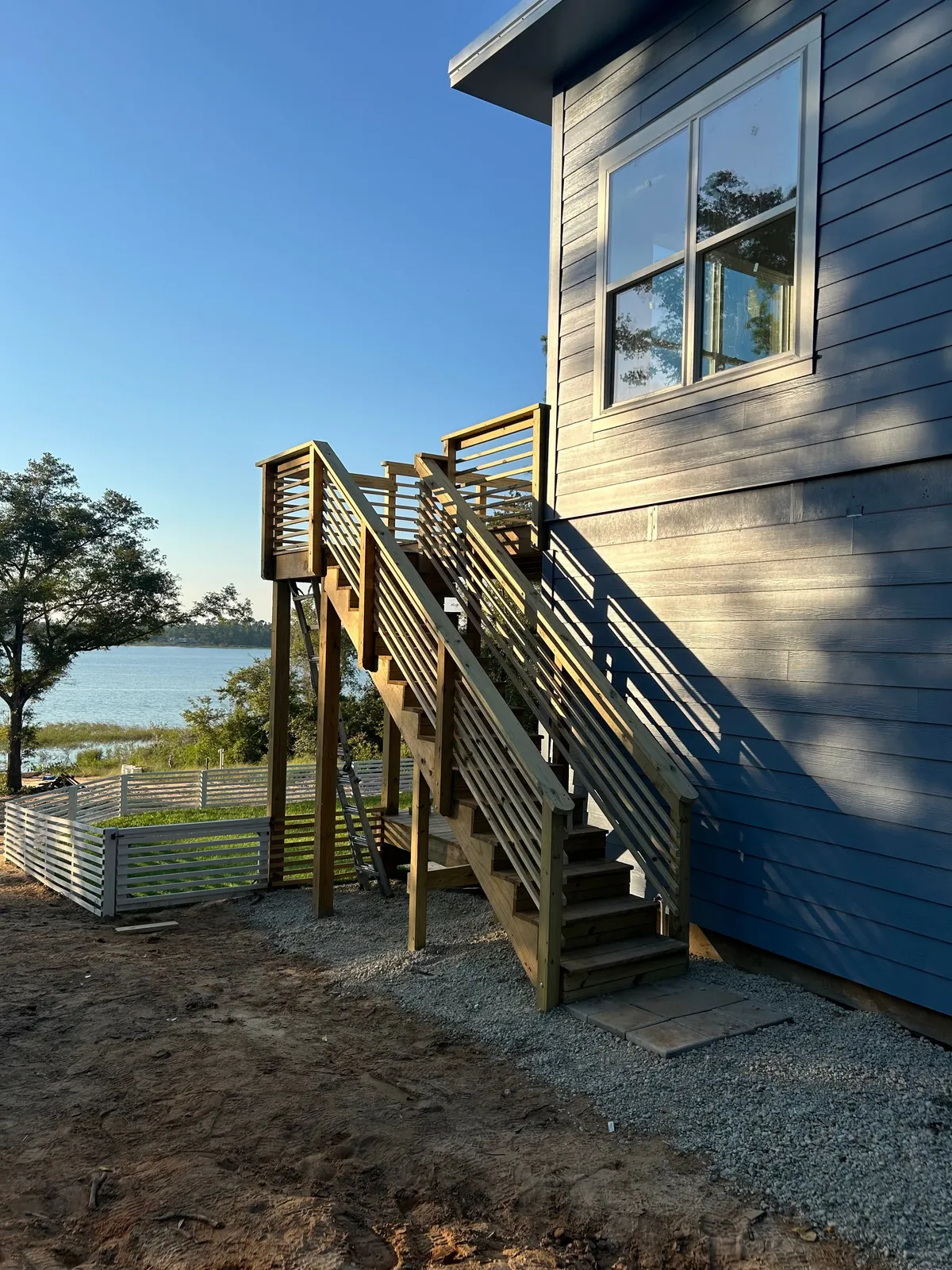 Wood exterior stairs beside blue siding, with the lake visible beyond.
