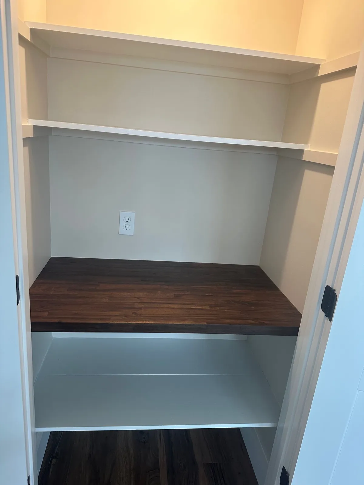 Tall pantry with white shelves above and below a dark wood counter.