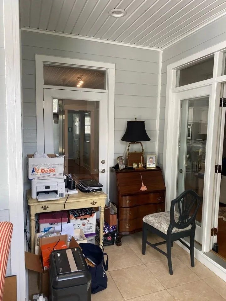 Corner of the enclosed porch before the remodel, with a glazed door and transom to the main house, a printer stand, and a secretary desk.