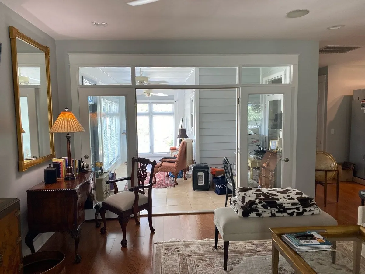 Living room before the remodel, with a glazed wall of doors and transom windows separating it from the enclosed porch.