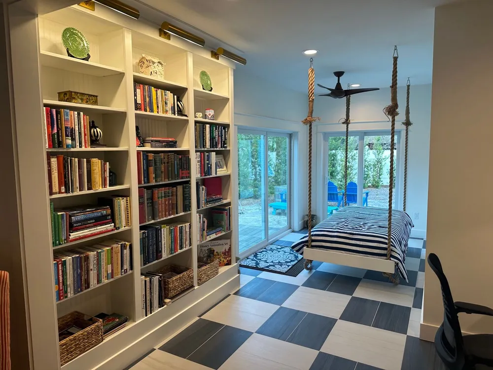Remodeled room with a lit built-in bookcase, a hanging bed on ropes, sliding glass doors, and a checkerboard tile floor.