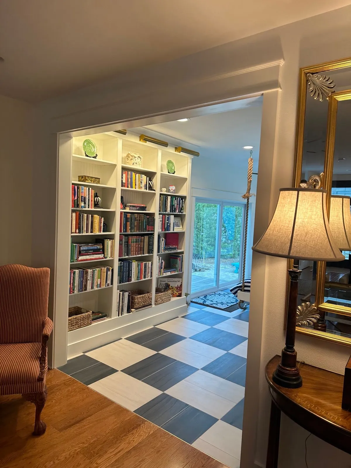 Built-in bookcase with brass picture lights, framed by trim at the opening from the living room.