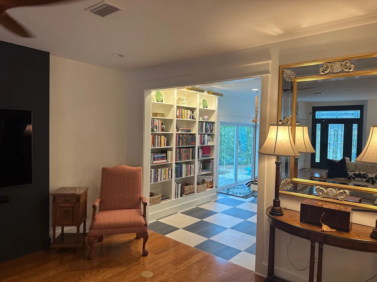 Living room with an armchair and console table, looking through the trimmed opening to the bookcase and sliding doors.