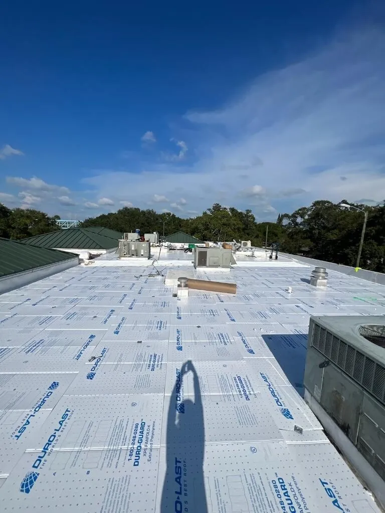 Printed Duro-Guard boards laid across the roof, with rooftop equipment at the edge and trees beyond.
