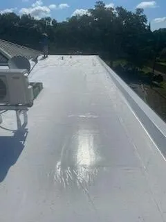 A long wing of white membrane roof along a parapet, with rooftop equipment at left.