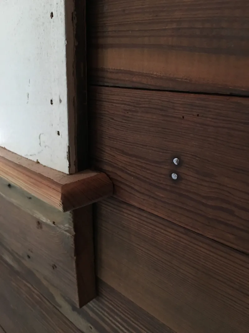 Close view of the rounded end of a window stool with the apron beneath it.