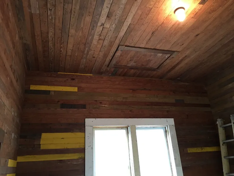 Room lined with reclaimed wood walls and a wood ceiling before finishing.