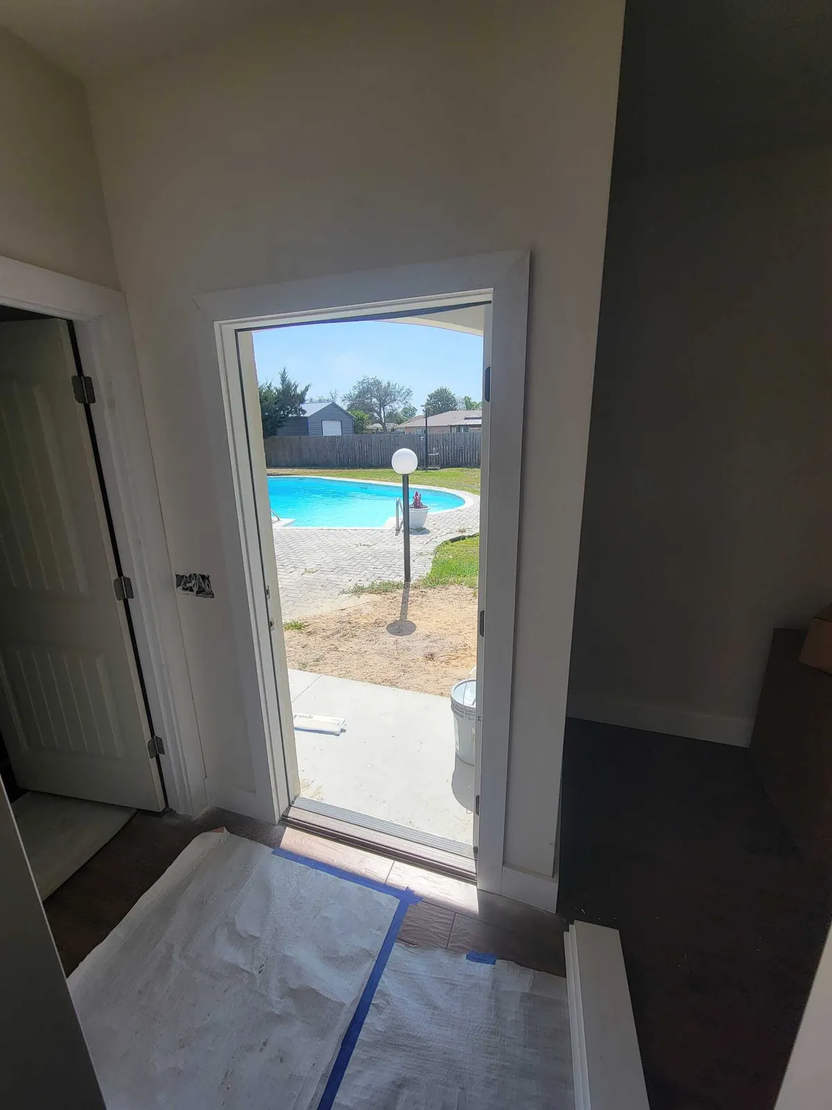 Open back door with new trim, looking out to the patio, with paper protecting the floor.
