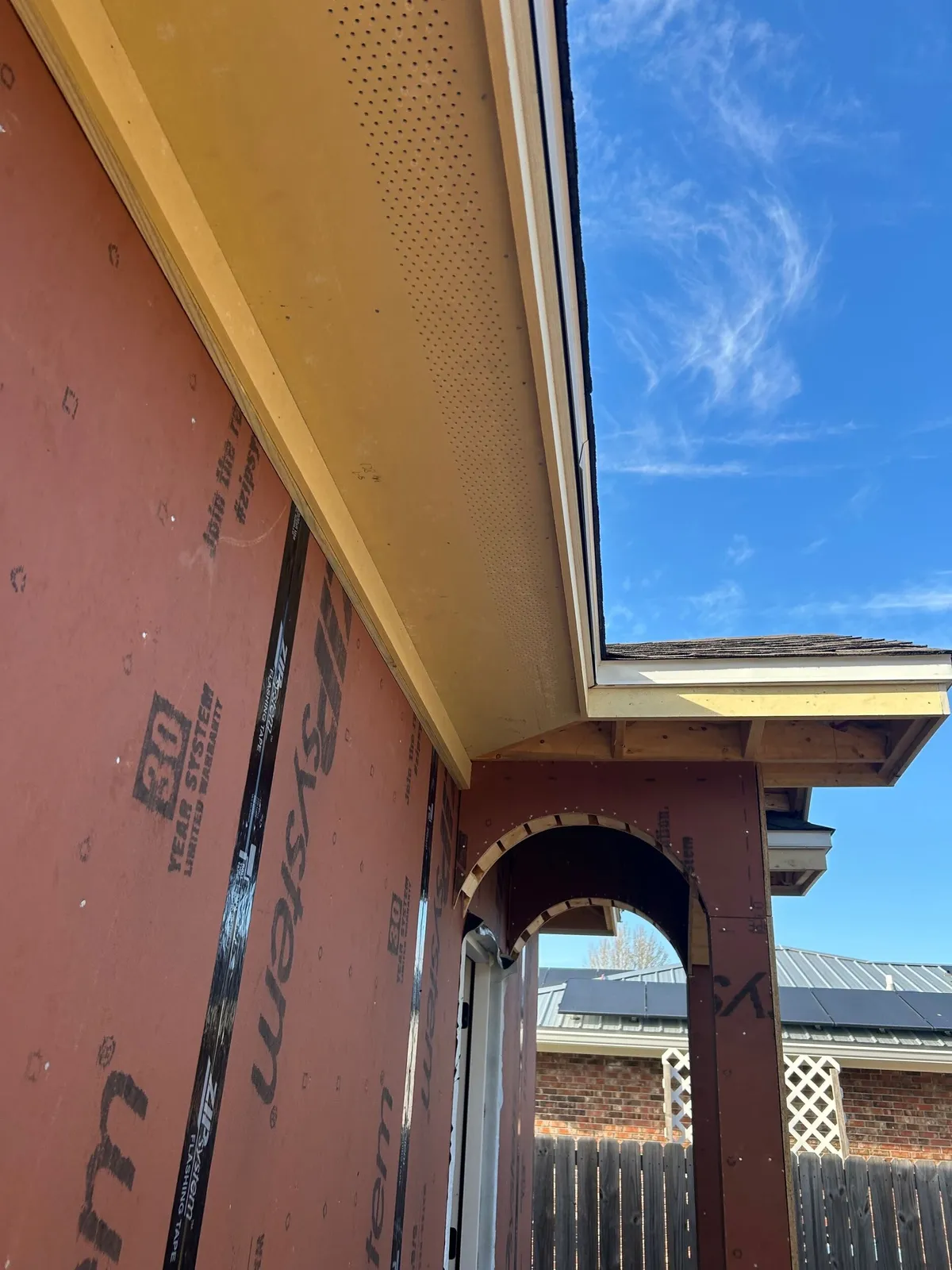 Soffit above the entry, looking through the framed arch toward the yard beyond.