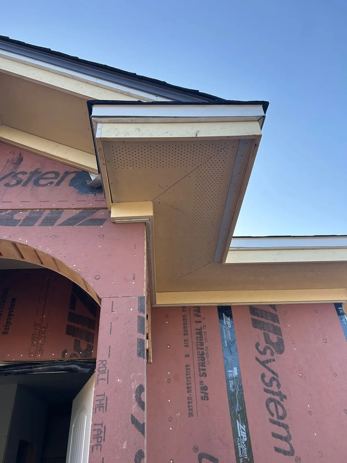 Gable return and vented soffit at the corner of the entry, with the sheathed arch below.