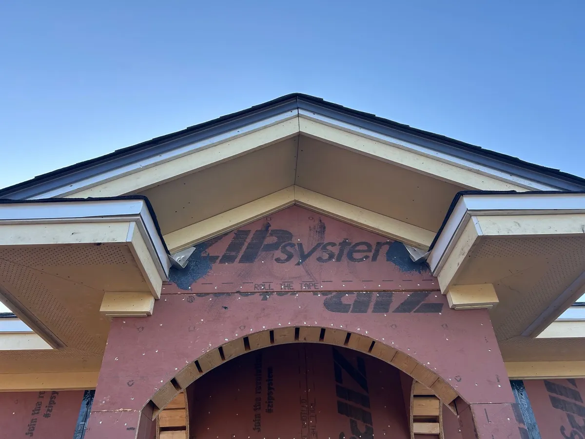 Gable returns, soffits, and trim over the sheathed entry arch, before stucco.