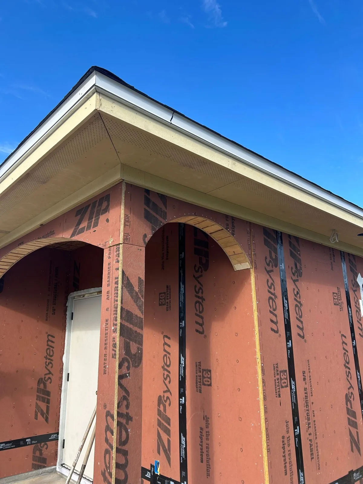 Back porch arches framed in the sheathed wall, beneath the soffit at the roof corner.