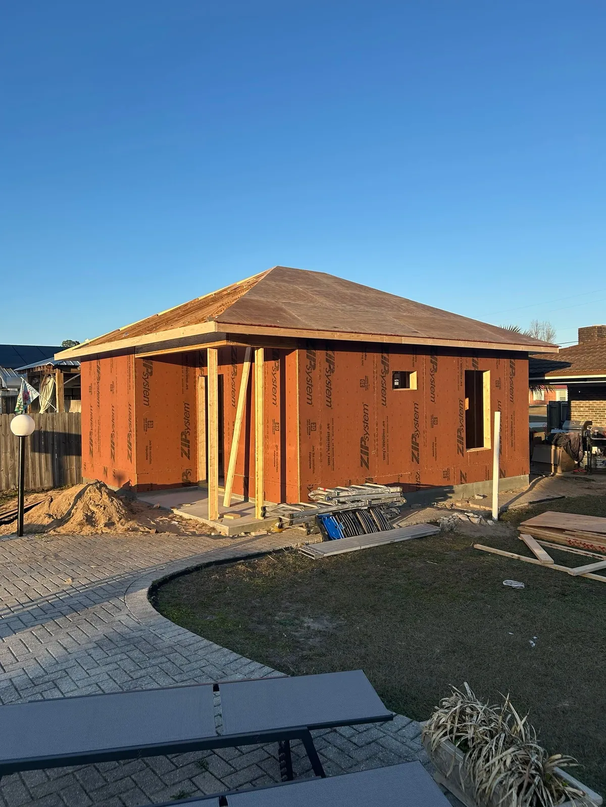 Front view of the studio with the roof decked, wood posts at the entry, and a paver walk in front.