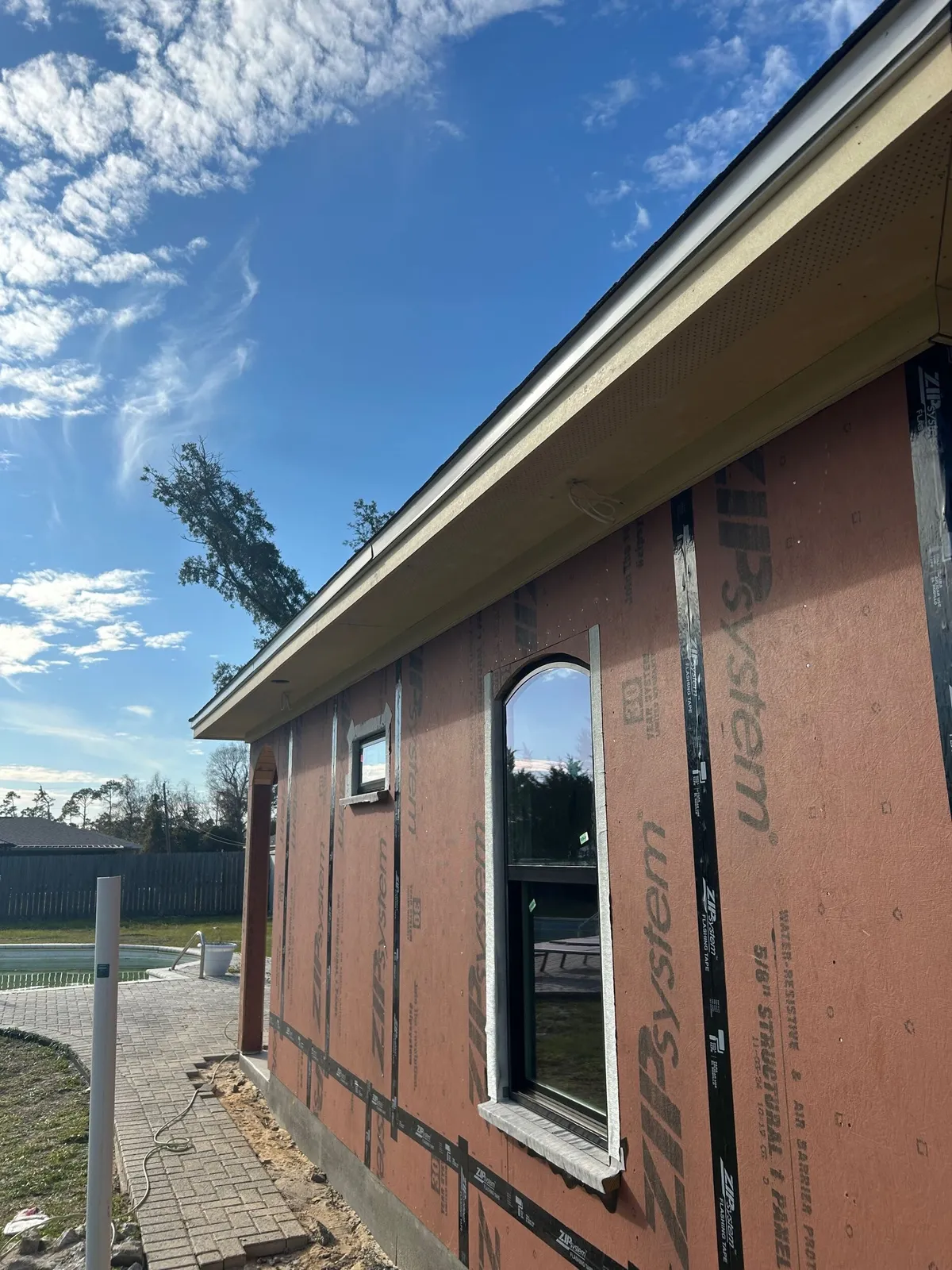 Side wall with an arched-top window set into the sheathing, under the eave and soffit.