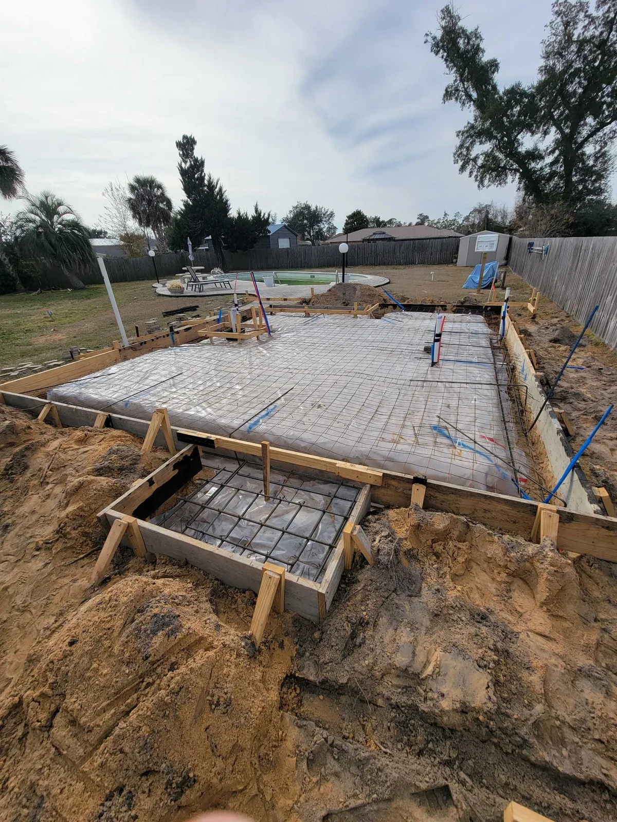 Formed slab area covered in plastic sheeting and reinforcing mesh, with a smaller porch section formed in front.
