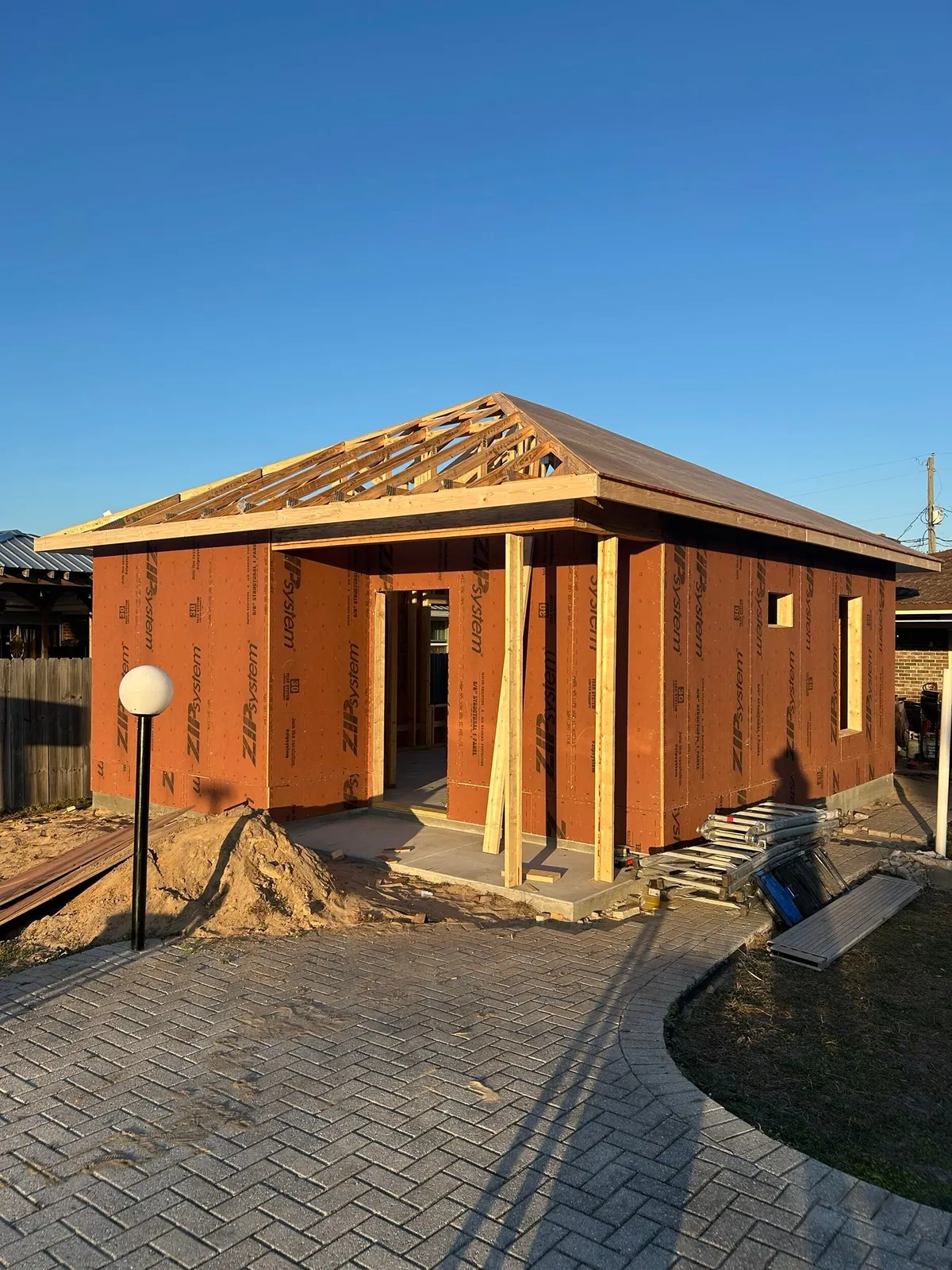 Front view of the sheathed studio with roof trusses in place and wood posts at the entry.