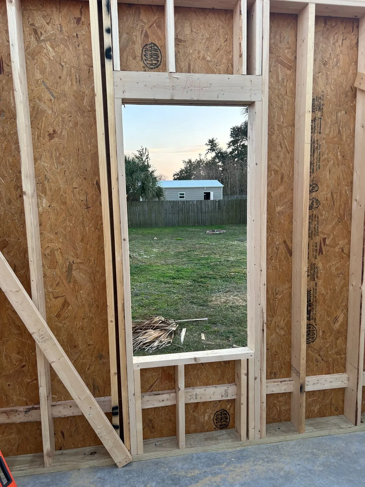 Tall framed window opening in a sheathed wall, seen from inside.