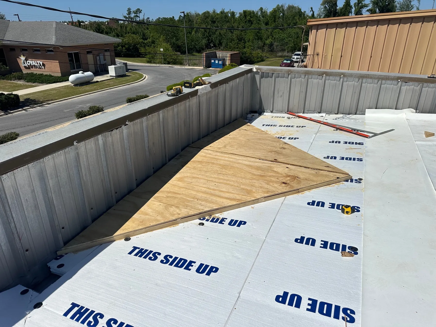 A cricket built up on the roof deck, its sloped plywood surface meeting the cover board before the membrane covers it.