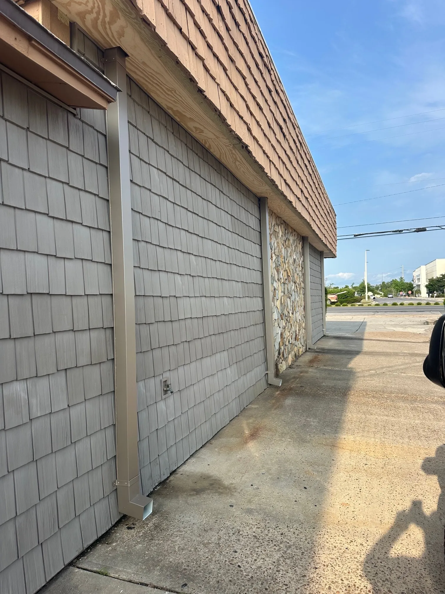 The replacement downspout running down the wall below the mansard soffit.