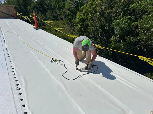 A crew member hot-air welding a seam in the white membrane.