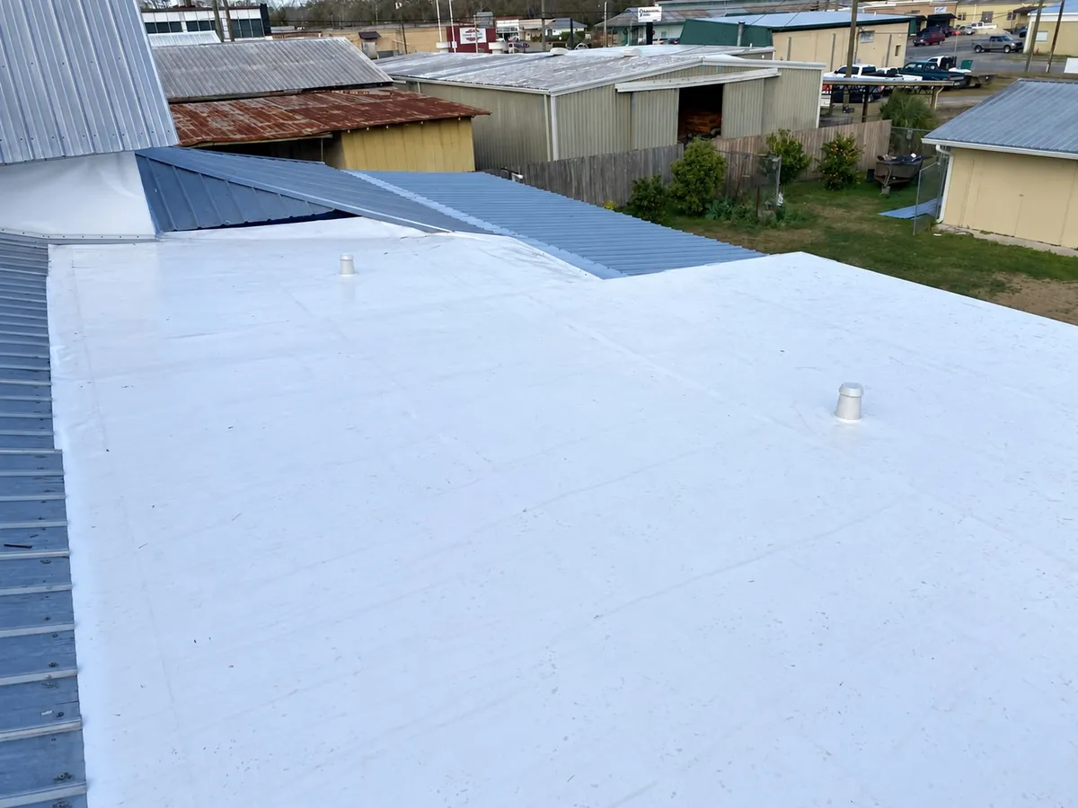 White membrane across the recover area, meeting the adjoining metal roof at its edge.