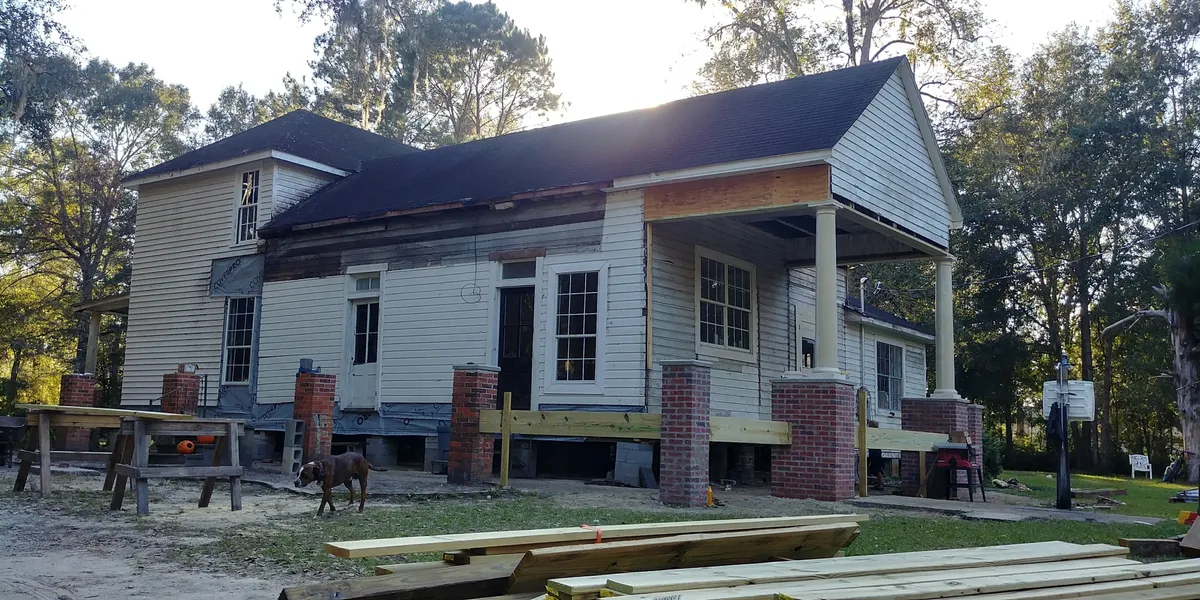 Angled view of the building with a new porch beam set on brick piers along one elevation and columns carrying the porch roof at the far end.